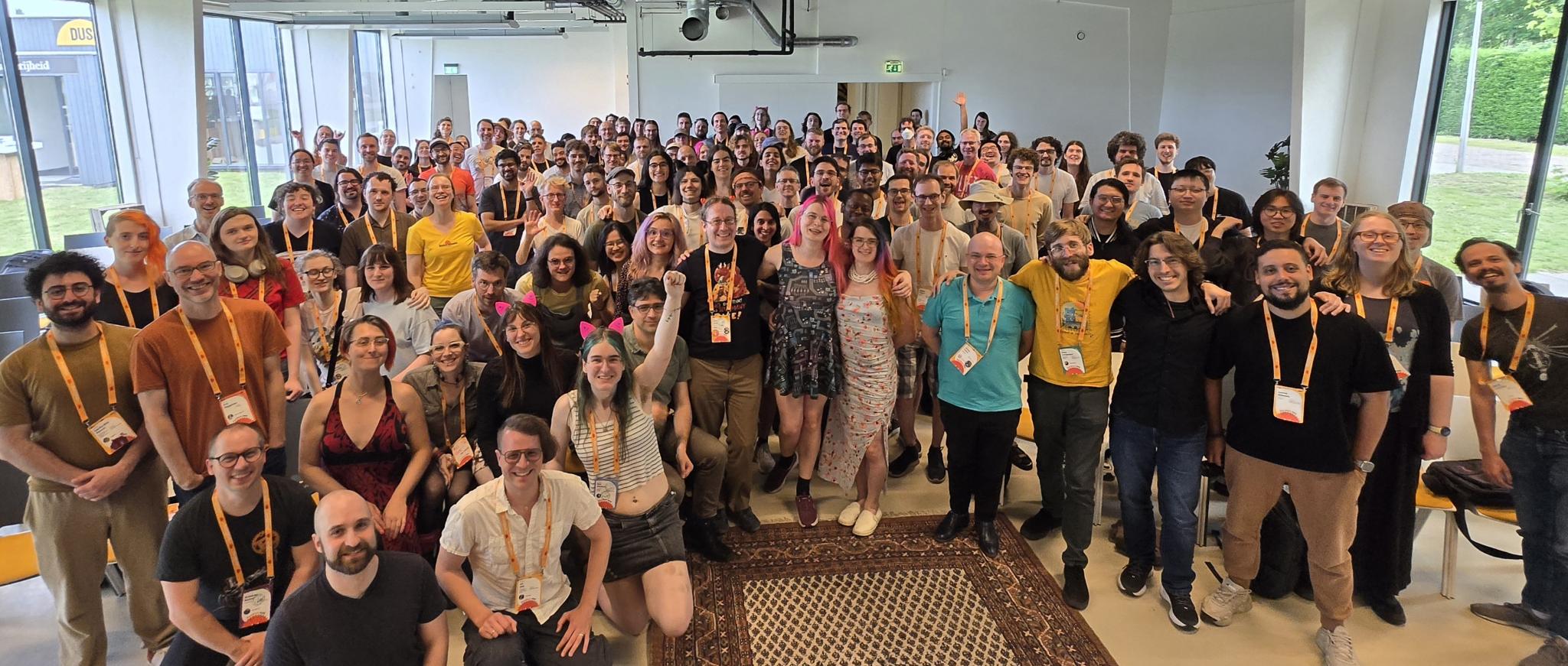 A large room full of Rustaceans and friends smiling into the camera